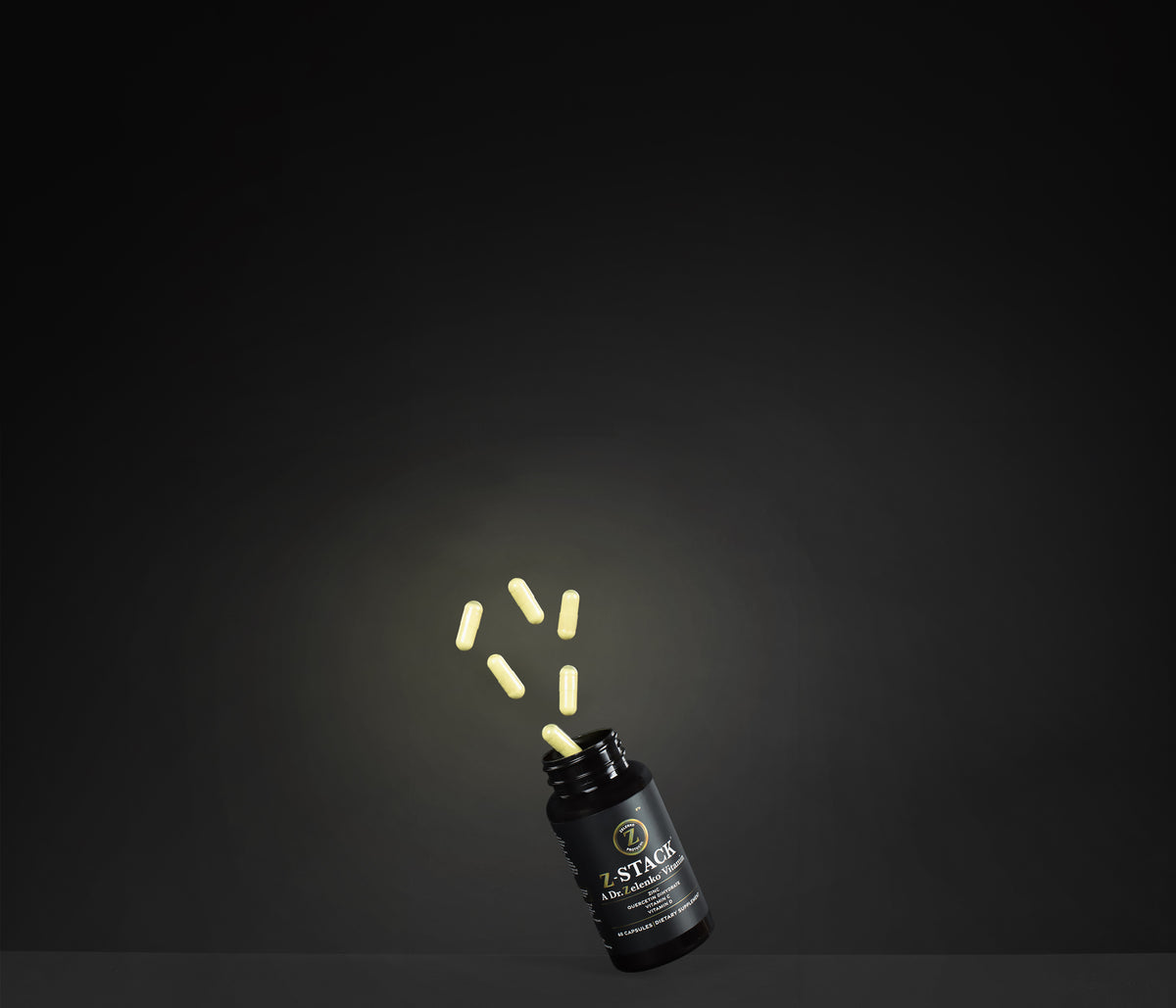 a black bottle of z-stack on a black background with the capsules flying out of the bottle